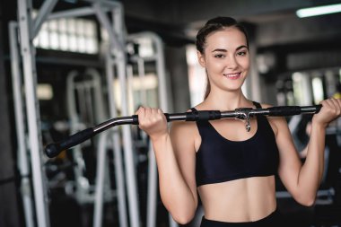 Genç ve çekici bir jimnastik makinesiyle egzersiz yapan çekici bir kadının sinematik tonu. Vücut kaslarını sağlıklı yaşam konseptine uydurmak için bireysel spor. 