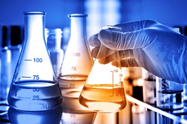 Laboratuvar geçmişi, bilim laboratuarı araştırma ve geliştirme konsepti ve laboratuvar malzemeleriyle dolu bir matarayı tutan bilim adamının eli. 