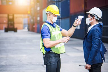 Coronavirus krizi sırasında voronavirüsü korumak için işe girmeden önce Covid 19 virüsünü dijital termometreyle tarayın. Mühendis endüstrisi ve fabrika konsepti. 