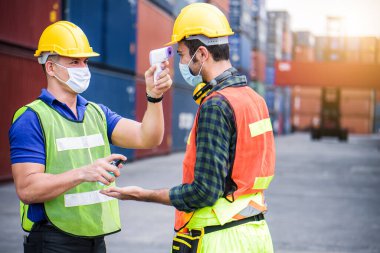 Coronavirus krizi sırasında voronavirüsü korumak için işe girmeden önce Covid 19 virüsünü dijital termometreyle tarayın. Mühendis endüstrisi ve fabrika konsepti. 