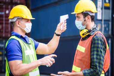 Coronavirus krizi sırasında voronavirüsü korumak için işe girmeden önce Covid 19 virüsünü dijital termometreyle tarayın. Mühendis endüstrisi ve fabrika konsepti. 
