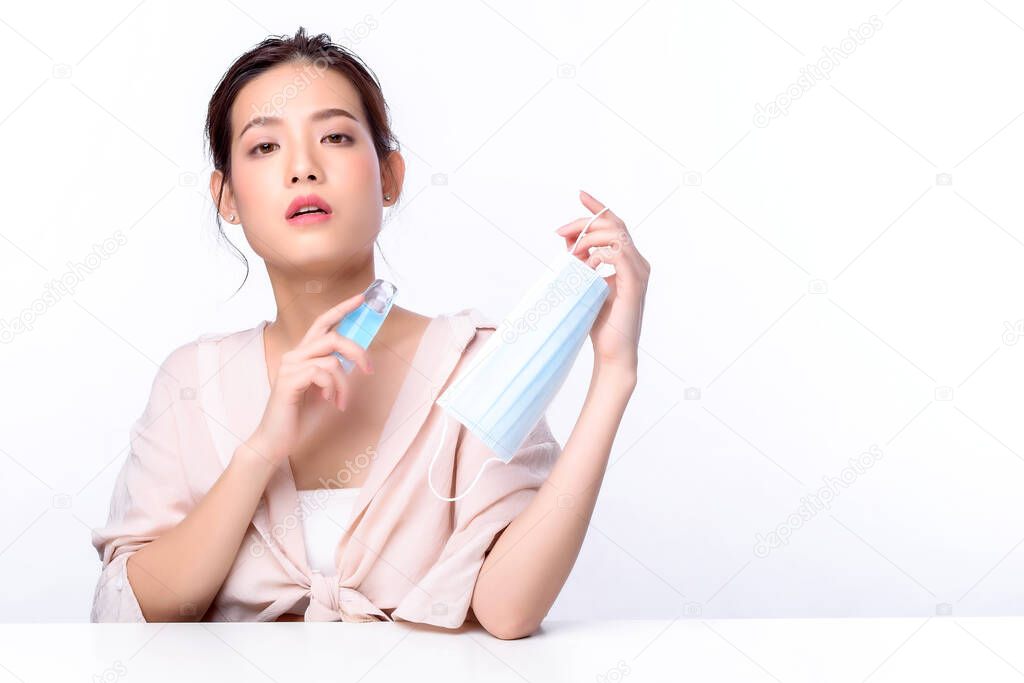 Portrait of beautiful charming young Asian woman posing facial and sitting with white table, beauty of female face with skincare on white background, healthcare and skin care concept. 