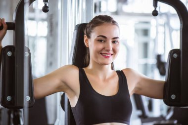 Genç ve çekici bir jimnastik makinesiyle egzersiz yapan çekici bir kadının sinematik tonu. Vücut kaslarını sağlıklı yaşam konseptine uydurmak için bireysel spor.  