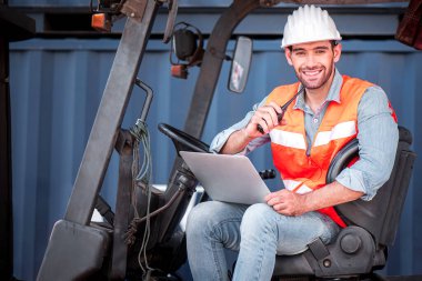 Beyaz güvenlik kaskı takan Kafkasyalı mühendis sürücüye telsiz çağrısı yapıyor ve kargo nakliye gemisinden ithalat ve ihracat için konteynır kutusunu kontrol ediyor. 