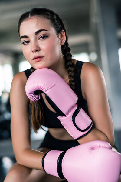 Attractive young Caucasian woman in boxing gloves. fashionable studio portrait of an sporty lady at gym background 