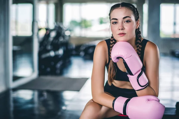Attractive young Caucasian woman in boxing gloves. fashionable studio portrait of an sporty lady at gym background