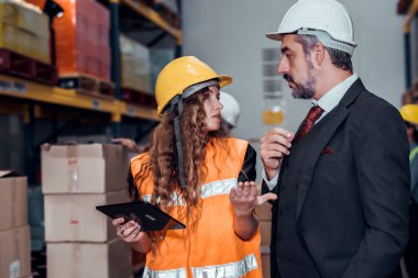Mühendis kadın ve işadamı yük deposunda sabit kasklı bir kargo taşıyorlar ve tablet raporuna göre ithalat ve ihracat için kargo gemisinden yükleme kontrolü yapıyorlar. Takım çalışması konsepti 