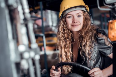 Mühendis kadın forklift kullanıyor ve yük ambarında dikiliyor. İthalat ve ihracat için kargo gemisinden yükleme kontrolü yapılıyor mu kontrol edin. Takım çalışması konsepti