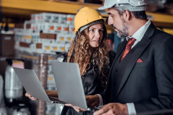 Mühendis kadın ve işadamı yük deposunda sabit kasklı bir kargo taşıyorlar ve dizüstü bilgisayardan gelen rapora göre ithalat ve ihracat için kargo gemisinden yükleme kontrolü yapıyorlar. Takım çalışması konsepti 