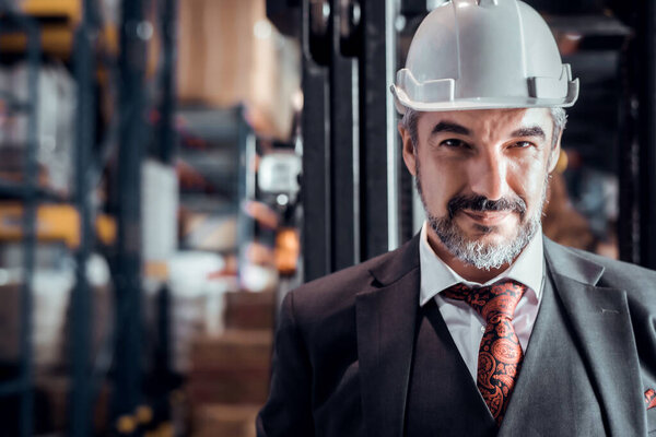 Confident Caucasian businessman owner wearing white safety helmet standing at goods warehouse store and check for control loading containers box from Cargo freight ship for import and export