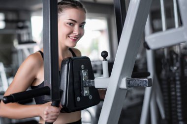 Genç çekici kadın spor salonundaki makineyle egzersiz yapıyor.. 
