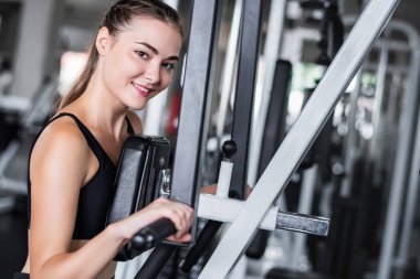 Genç çekici kadın spor salonundaki makineyle egzersiz yapıyor.. 