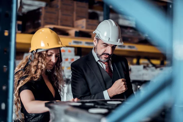 Engineer woman and businessman wearing a hardhat standing cargo at goods warehouse and check for control loading from Cargo freight ship for import and export. Teamwork concept