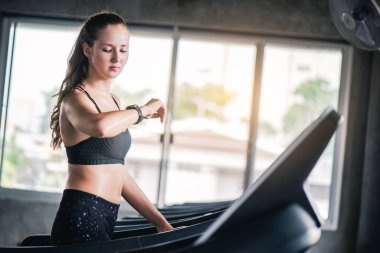 Güzel, beyaz bir kadın spor salonunda koşu bandında koşuyor.. 