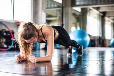Genç ve çekici bir jimnastik makinesiyle egzersiz yapan çekici bir kadının sinematik tonu. Vücut kaslarını sağlıklı yaşam konseptine uydurmak için bireysel spor.  