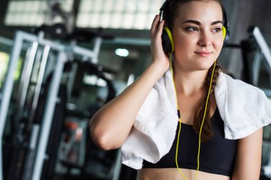 Kulaklıkla müzik dinleyen genç ve çekici bir kadın akıllı telefon ya da cep telefonuna bağlanıyor. Spor salonunda sıkı çalıştıktan sonra rahatlama.  