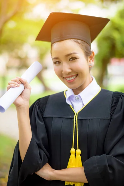 Graduated woman students wearing graduation hat and gown with happiness feeling with park background