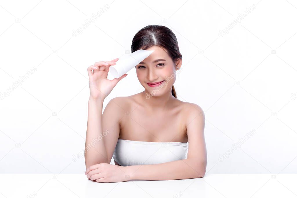 Portrait of beautiful charming young Asian woman posing facial with cosmetic and sitting with white table, beauty of female face with skincare on white background, healthcare and skin care concept. 