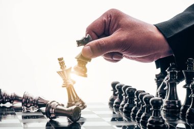 İş adamı satranç taşını hareket ettiriyor ve oyunu kazanmak için stratejik düşünüyor. Fikirler, rekabet ve strateji için satranç tahtası konsepti, iş başarısı konsepti 