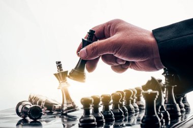 İş adamı satranç taşını hareket ettiriyor ve oyunu kazanmak için stratejik düşünüyor. Fikirler, rekabet ve strateji için satranç tahtası konsepti, iş başarısı konsepti 
