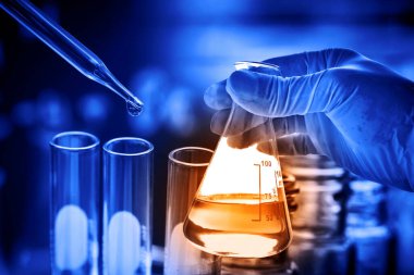 Laboratuvar geçmişi, bilim laboratuarı araştırma ve geliştirme konsepti ve laboratuvar malzemeleriyle dolu bir matarayı tutan bilim adamının eli. 