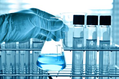 Laboratuvar geçmişi, bilim laboratuarı araştırma ve geliştirme konsepti ve laboratuvar malzemeleriyle dolu bir matarayı tutan bilim adamının eli.