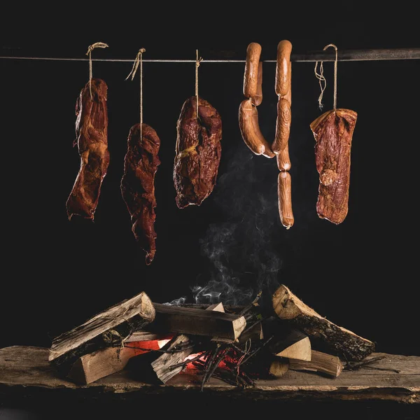 Smoked ham, bacon, pork neck and sausages in a smokehouse.