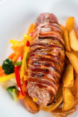 Domuz pastırmasına sarılmış ızgara domuz filetosu.