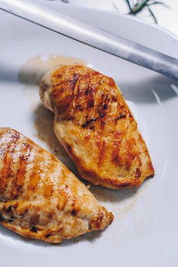 Beyaz tabakta ızgara tavuk göğsü.