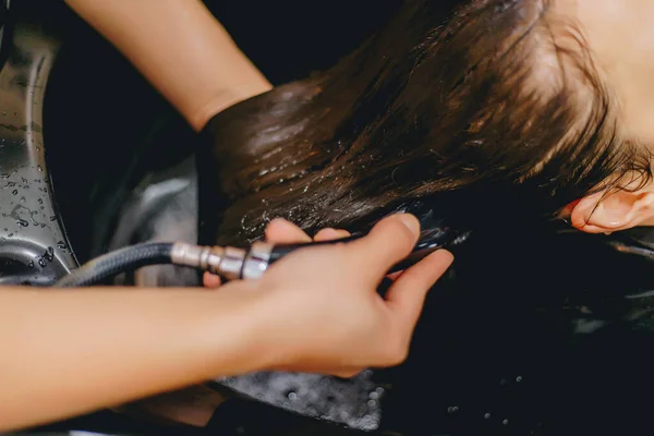 Professional hairdresser washes the girl\'s hair