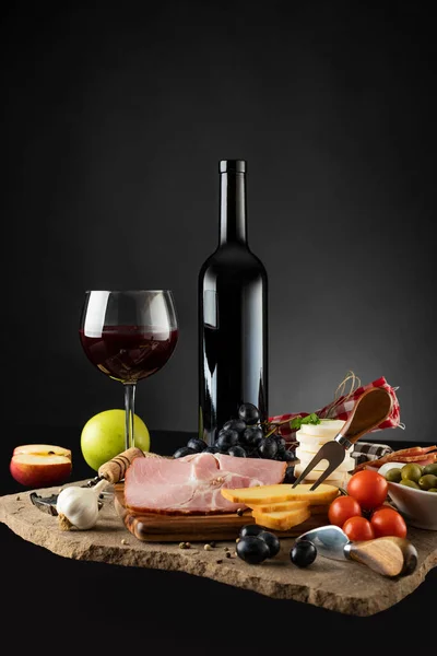 Kırmızı şarap ve aperatifler siyah arka planda.