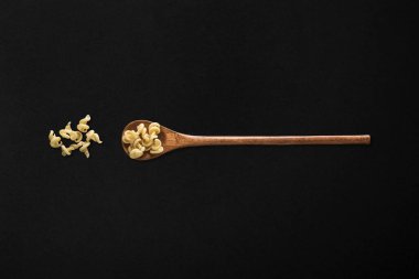 Siyah arka planda tahta kaşıkta makarna.