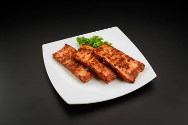 Beyaz tabakta servis edilen ızgara domuz eti.