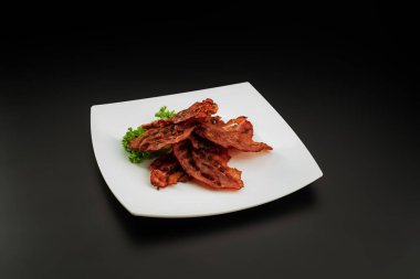 Beyaz tabakta ızgara domuz pastırması.