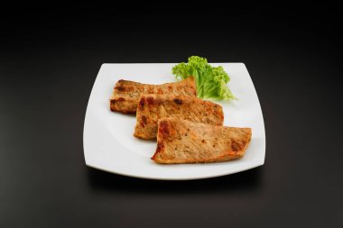 Beyaz tabakta ızgara domuz eti.