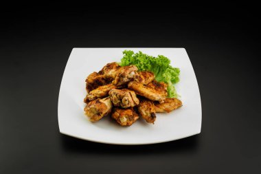 Beyaz tabakta ızgara tavuk kanadı..