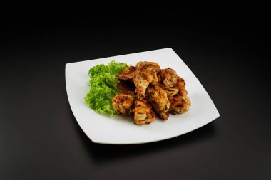 Beyaz tabakta ızgara tavuk kanadı..