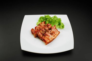 Beyaz tabakta ızgara domuz pastırması.