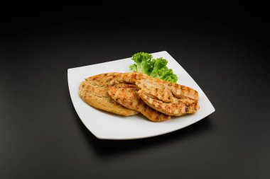 Beyaz tabakta ızgara tavuk göğsü.