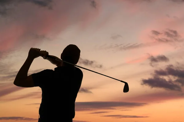 高尔夫球手在黄昏的天空中摇曳着高尔夫球杆的轮廓 — 图库照片