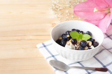 Müsli ve beyaz kasede böğürtlenli sağlıklı kahvaltı yoğurdu.