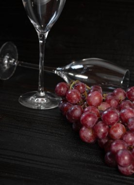 Bir sürü kırmızı üzüm ve koyu ahşap kaplama şampanya bardağı.