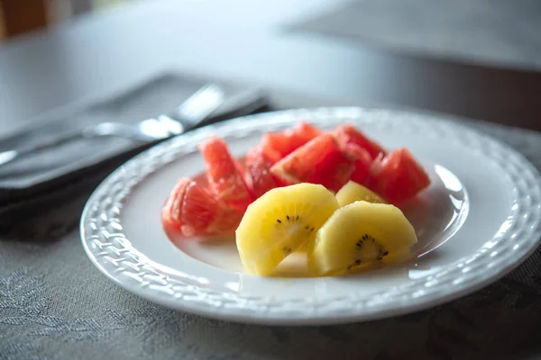 Fruits on white plate. Gold kiwi fruit, blurred pink grapefruit. Healthy life style