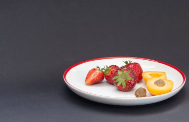 Beyaz bir tabakta çilek ve kayısı.