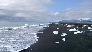 Siyah kum ve dalgalarla kaplı buzla kaplı plaj, İzlanda