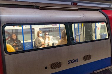 COVID-19 Coronavirus salgını sırasında Londra Metro Trene binen insanlar maske takıyor. 1.