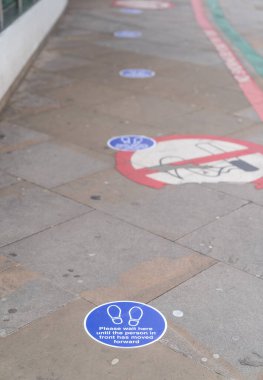 LONDON, ENGLAND - 6 Haziran 2020: COVID-19 Coronavirus salgını sırasında Londra 'daki Moorfield Göz Hastanesi' nin önünde kuyruk için fiziksel mesafeyi gösteren dairesel sosyal uzaklık etiketleri