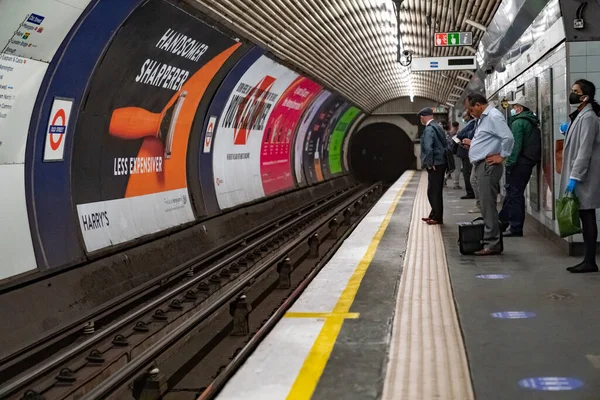 COVID-19 Coronavirus salgını sırasında maske takan insanların olduğu Londra Metro Platformu, 8 Haziran 2020