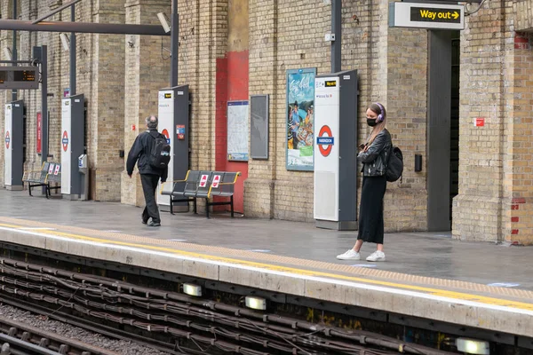 Londra Metro Platformu 'nda COVID-19 Coronavirus salgını sırasında maske takan genç bir kadın.