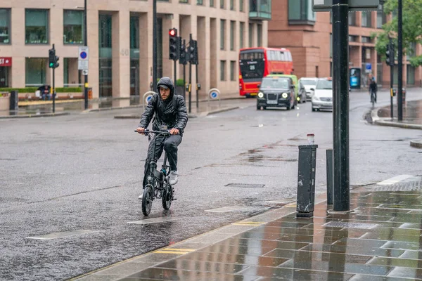 Londra, Holborn 'da, COVID-19 salgını sırasında yağmurda yağmurun kesildiğini gösteren yaşlı bisikletçi 10 Haziran 2020